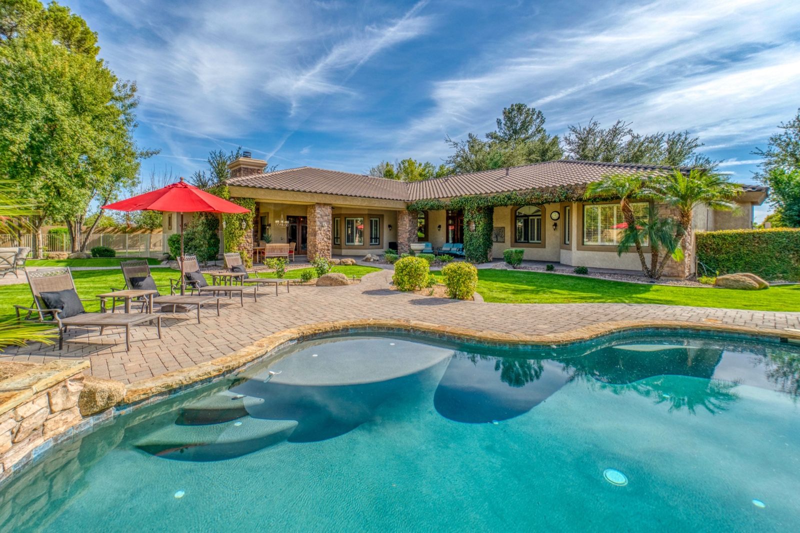 Backyard pool with a stone paver deck and covered patio